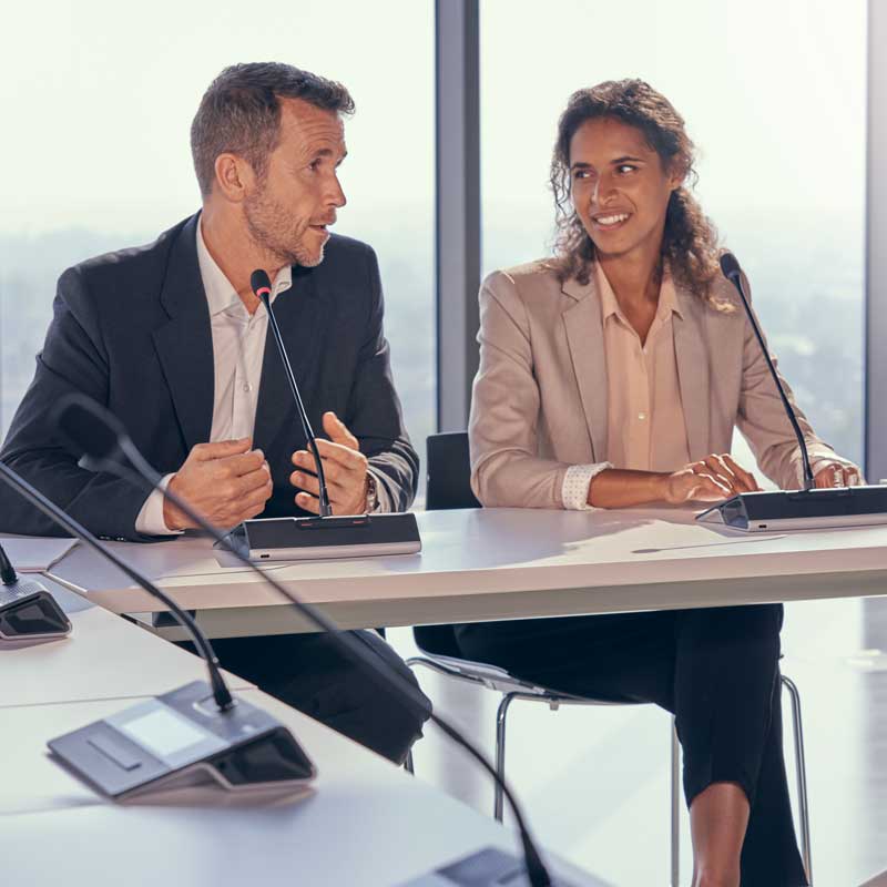 Two professionals speaking at a conference table